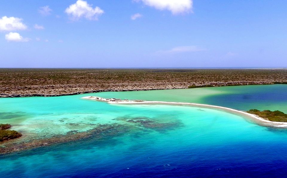 Vista aérea de bajos arrecifales turquesa y una lengua de arena blanca frente a la costa de La Tortuga
