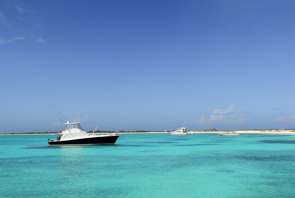 Sport-fishing boat anchored in turquoise water off a white-sand beach on La Tortuga