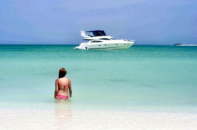 Shallow turquoise water at Cayo Herradura, with a swimmer and an anchored yacht