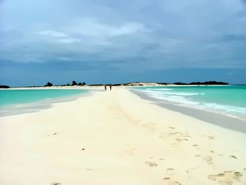 White sand spit of Cayo Herradura between turquoise waters, with two people in the distance