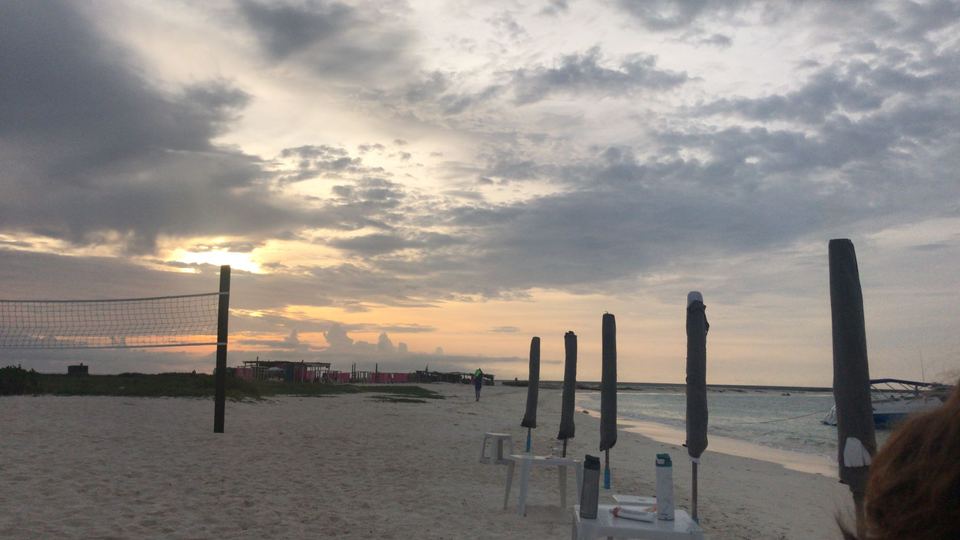 Cloudy evening sky over the beach, with shade-canopy poles